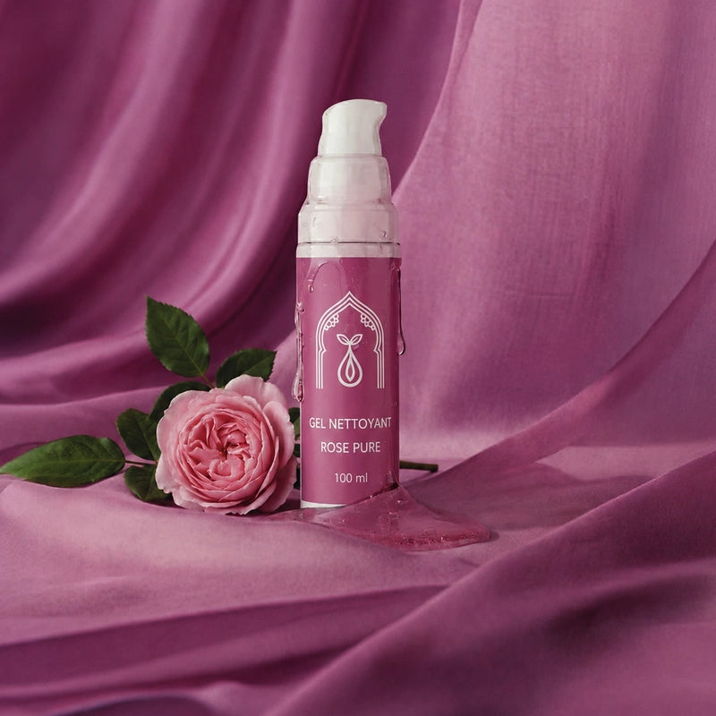 Flacon-pompe de gel nettoyant rose poudré, avec rose rose et feuilles vertes, bouchon blanc.