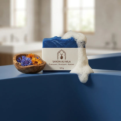 Savon bleu avec mousse blanche, étiquette beige « SAVON AU NILA », 120 g.