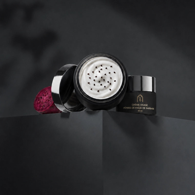 Pot de crème visage noir avec couvercle ouvert, crème blanche aux graines noires.