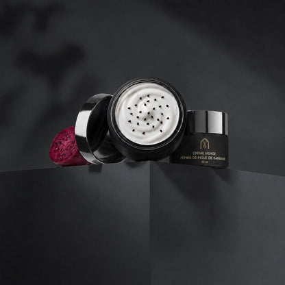 Pot de crème visage noir avec couvercle ouvert, crème blanche aux graines noires.