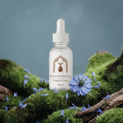 Flacon d’huile de nigelle 100 ml entouré de fleurs bleues sur une branche.