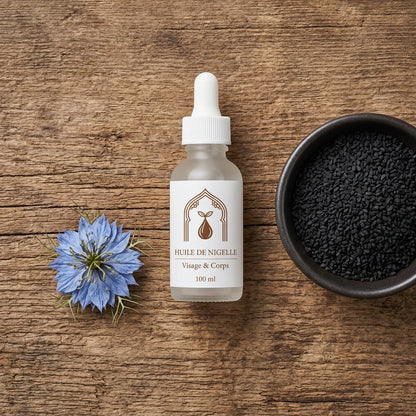 Flacon d’huile de nigelle 100 ml, fleur bleue et graines noires dans un bol.