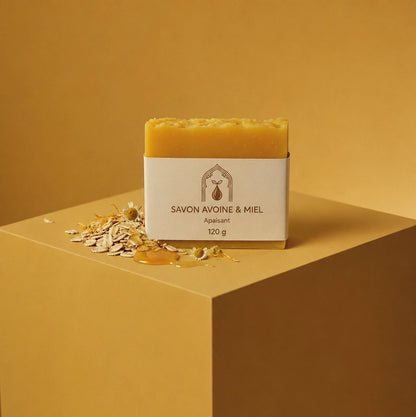 Savon solide jaune sur socle, étui blanc et avoine émiettée autour