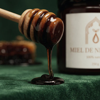 Cuillère en bois de miel de nigelle, filet de miel vers l’avant, pot visible