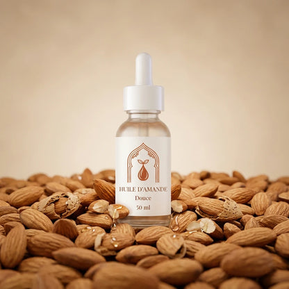 Flacon d’huile d’amande douce 50 ml, compte-gouttes, posé sur un lit d’amandes.