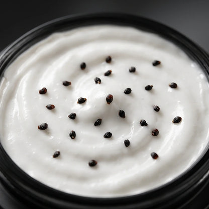 Crème visage blanche en pot, parsemée de graines noires en gros plan.