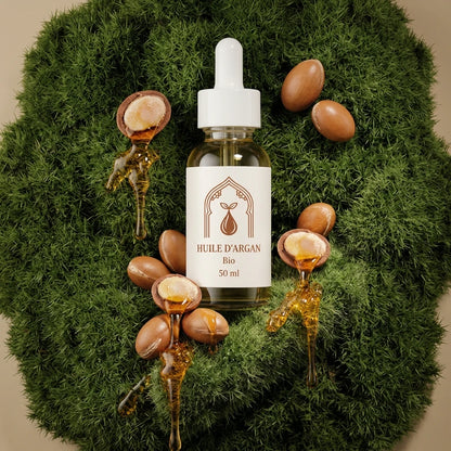 Flacon d’huile d’argan bio 50 ml, pipette blanche, entouré de noix d’argan