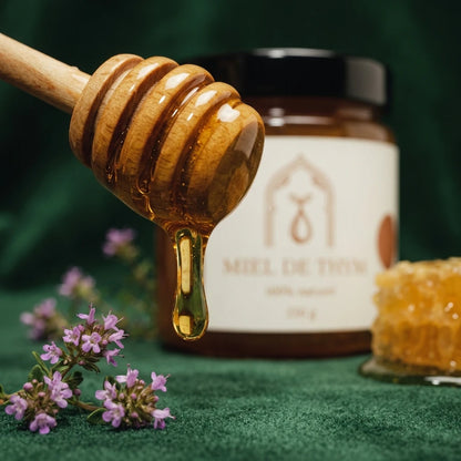 Miel de thym: cuillère en bois ruisselant de miel au-dessus du pot, gros plan