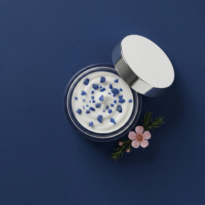 Pot de crème de jour hydratante ouvert, crème blanche texturée et couvercle blanc, vue de dessus