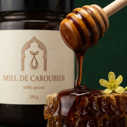 Miel de caroubier en train de couler d’une cuillère en bois, pot 250 g
