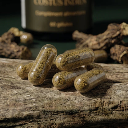 Gélules translucides beiges avec poudre dorée, flacon noir en arrière-plan