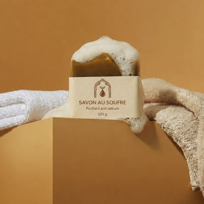 Pain de savon au soufre brun, étiquette crème, mousse blanche; dans un coffret en carton.