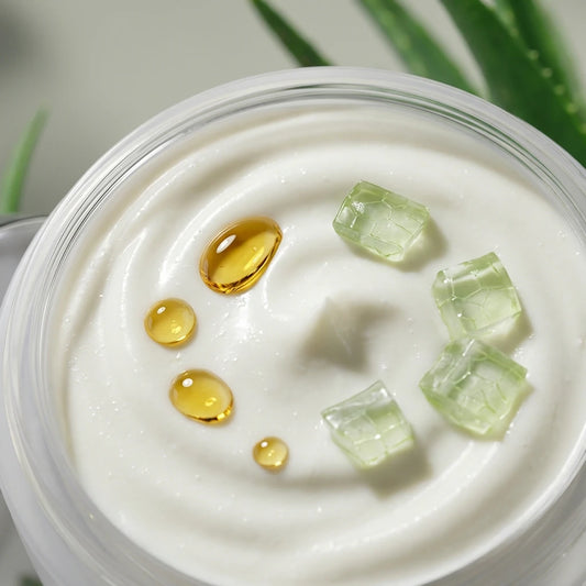 Pot de crème visage blanche avec perles dorées et cubes d’aloe vera transparents