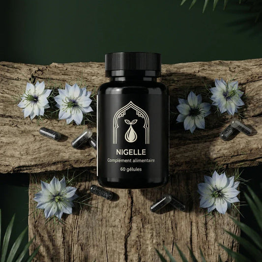 Flacon noir Nigelle 60 gélules sur bois, capsules sombres dispersées et fleurs blanches.