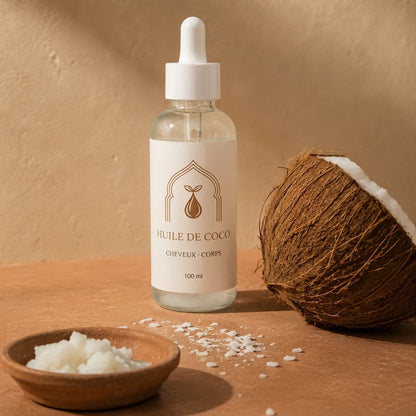 Flacon d’huile de coco 100 ml, noix de coco et copeaux blancs sur table.