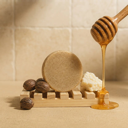 Shampoing solide beige sur support en bois, avec miel doré en filet